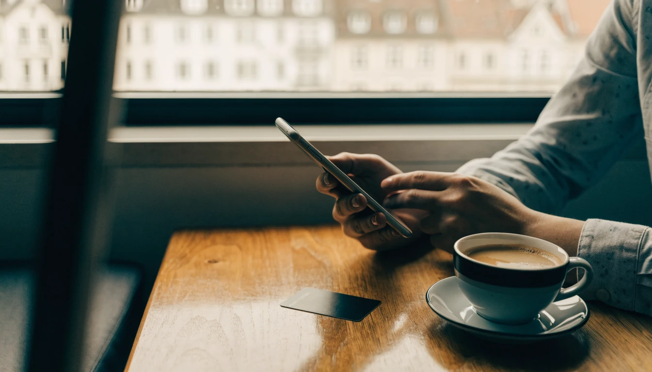 Hände mit Smartphone und Bezahlkarte am Tisch